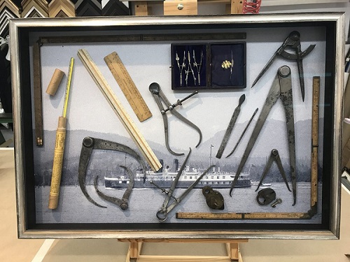 A shadowbox collection of steamship-era navigational tools for working with marine charts.